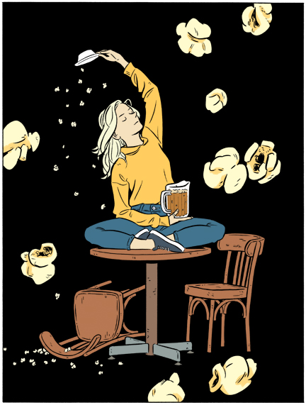 A young blond woman sits on a table cross legged with a pitcher of beer while large popcorn kernels float around her in the air